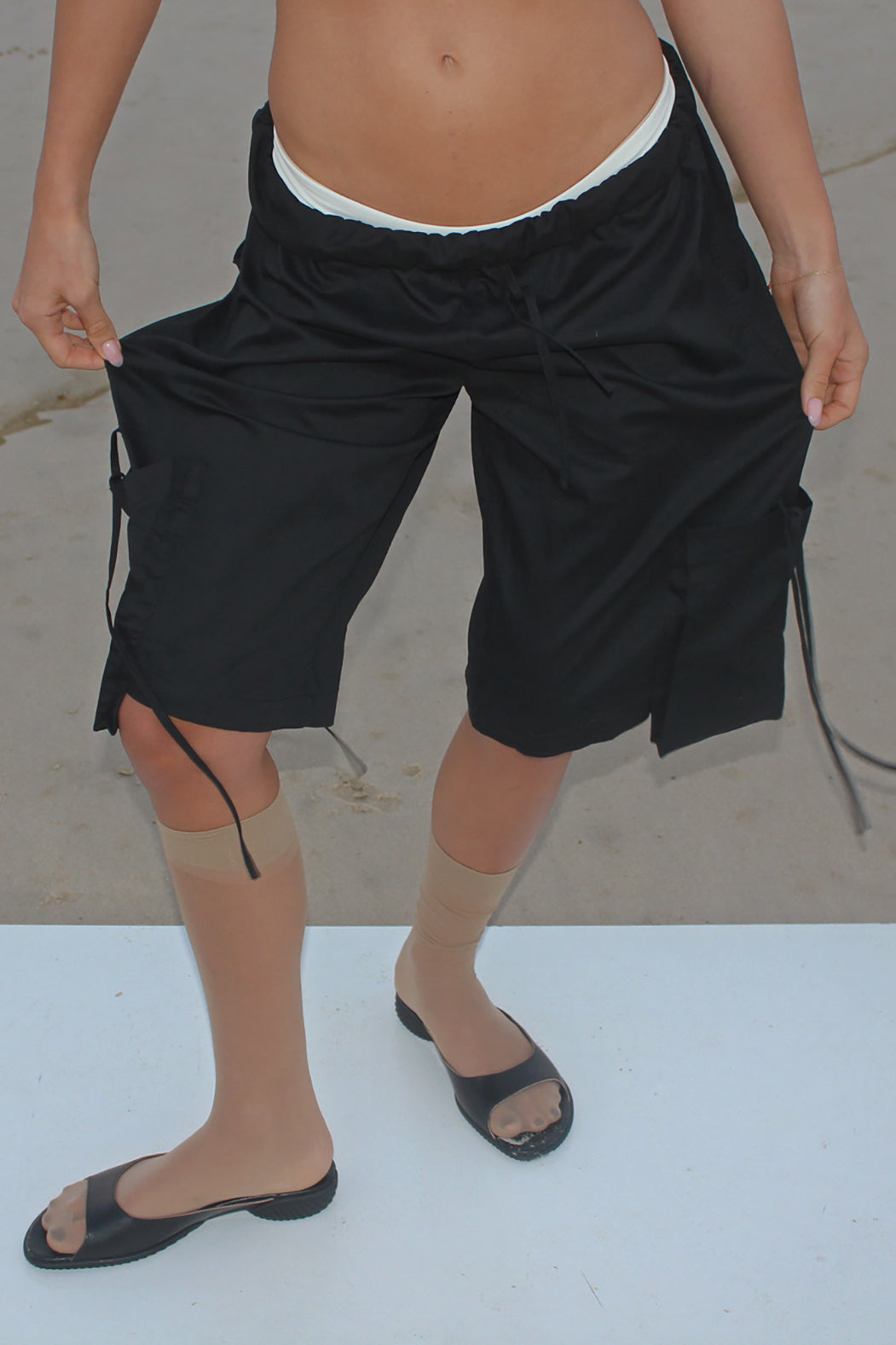 Person wearing black shorts on a plain background