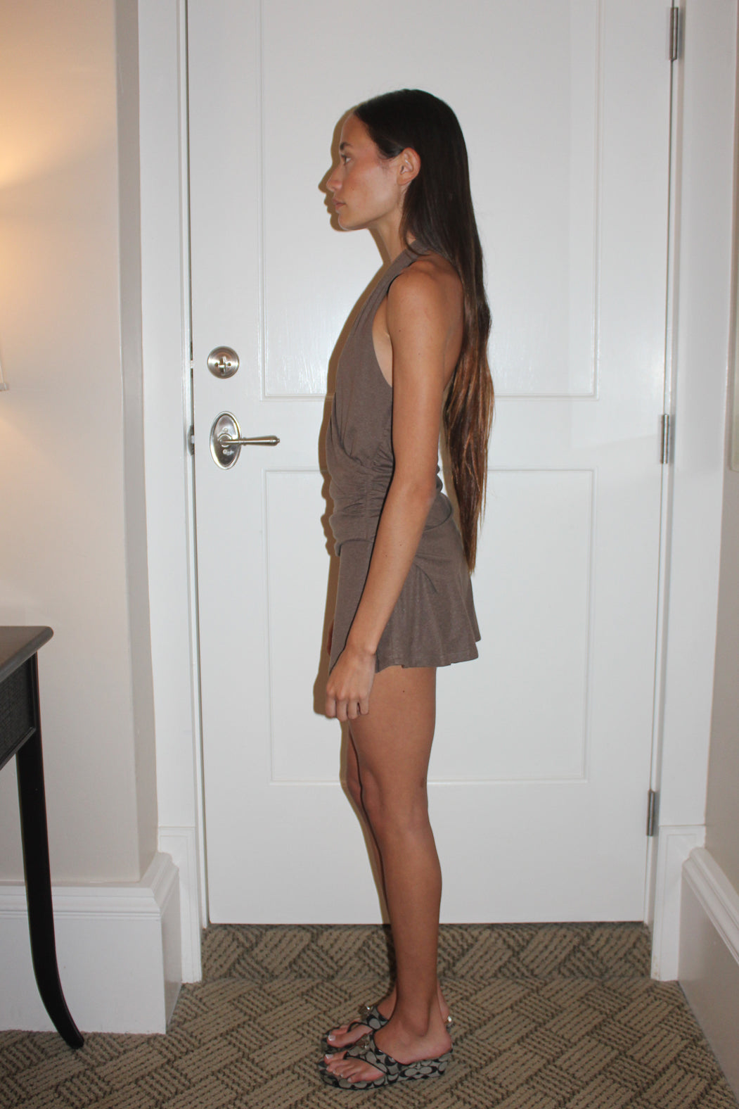 Woman wearing a brown halter top and skort standing in a room with a white door.